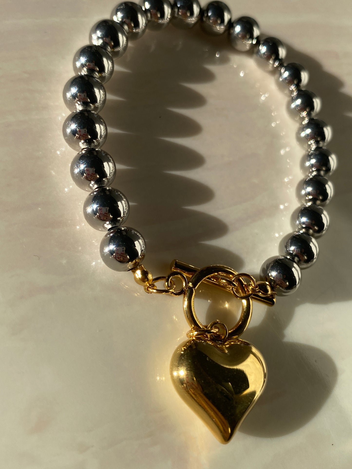 Pulsera plateada con corazón dorado