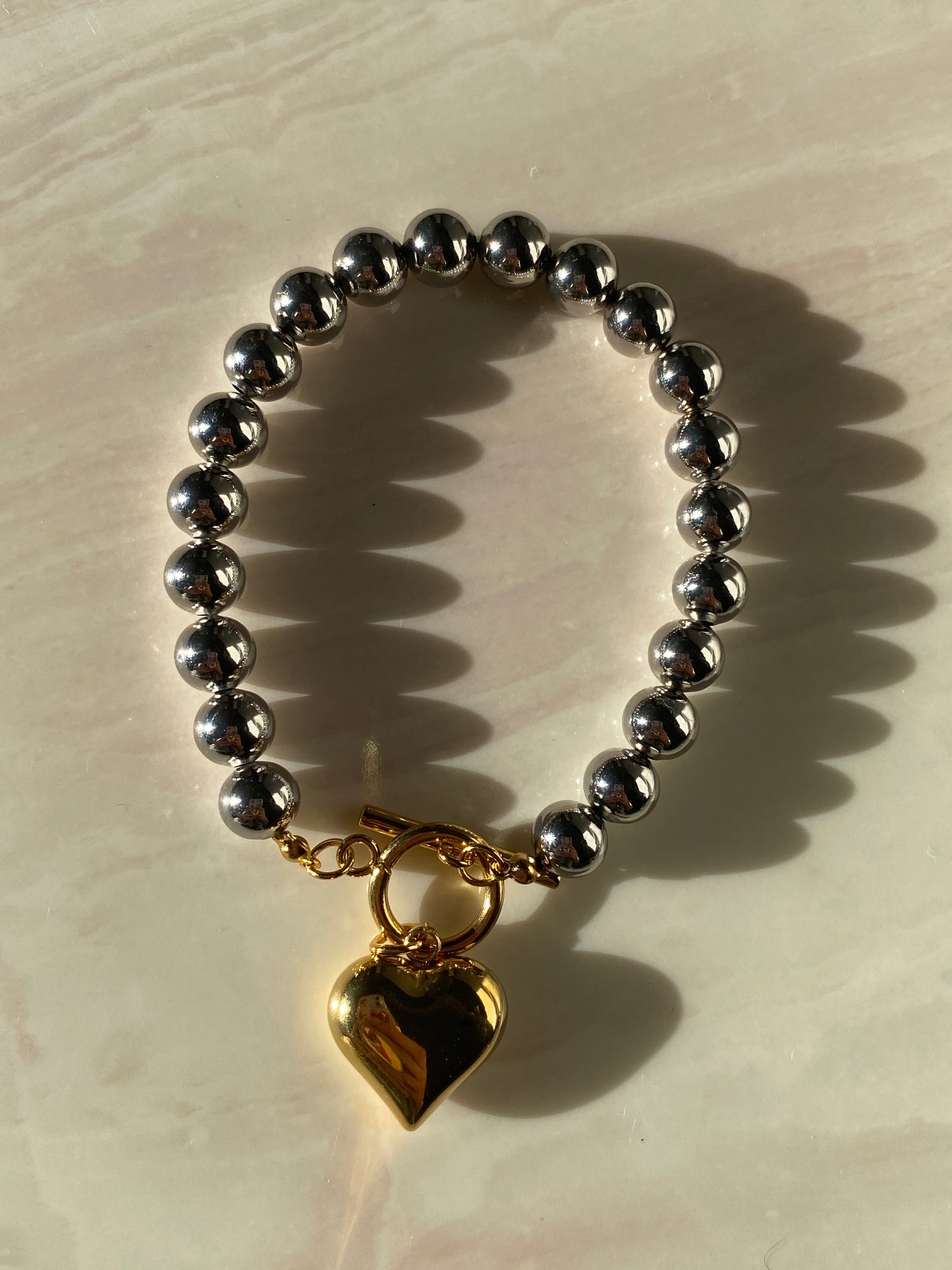 Pulsera plateada con corazón dorado